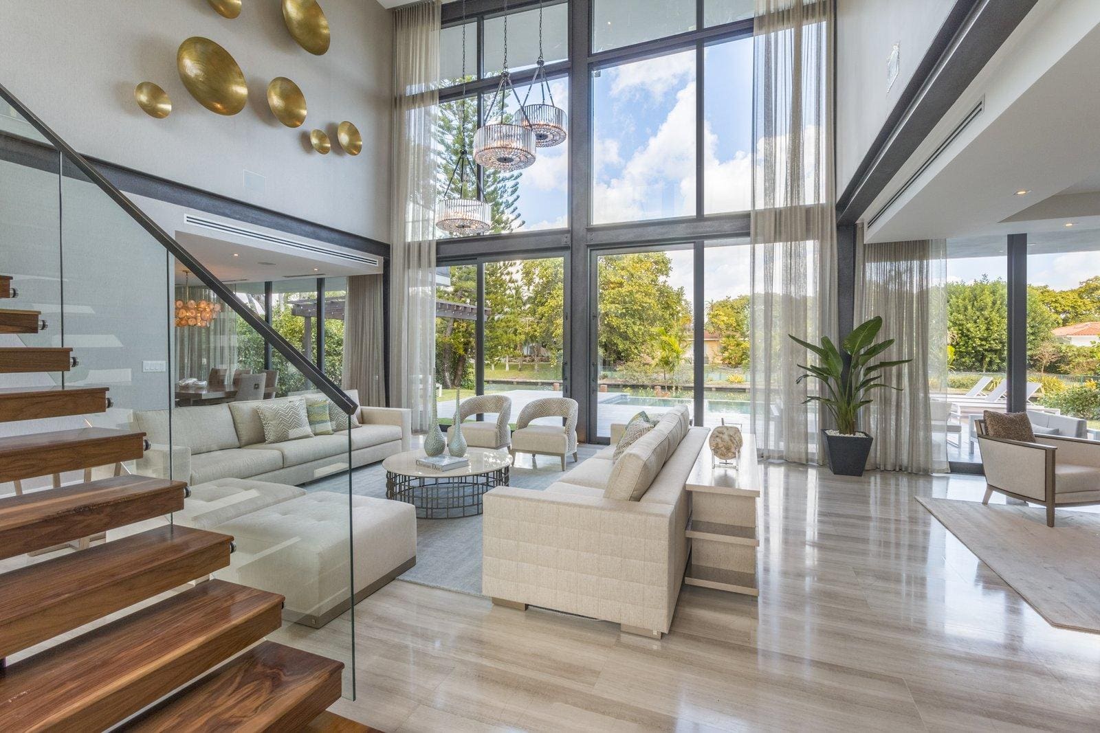 Modern living room with large windows and staircase.